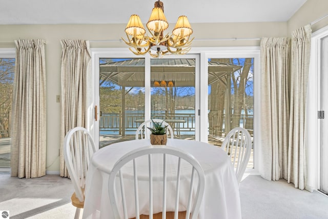 dining area featuring light colored carpet, a notable chandelier, and a healthy amount of sunlight