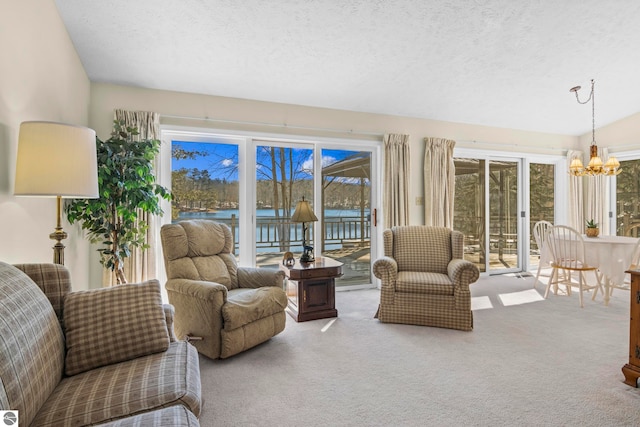 living room with plenty of natural light, a water view, carpet floors, and a chandelier