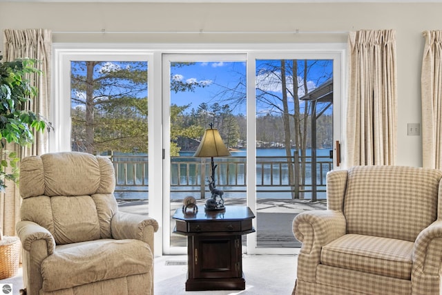 sitting room with carpet floors, visible vents, and a water view
