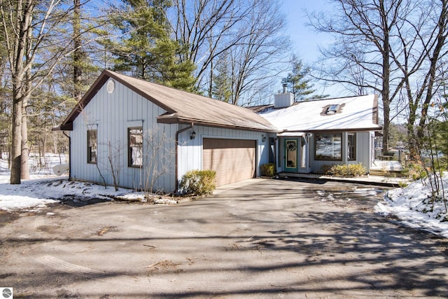 view of front of home featuring a chimney, an attached garage, and driveway