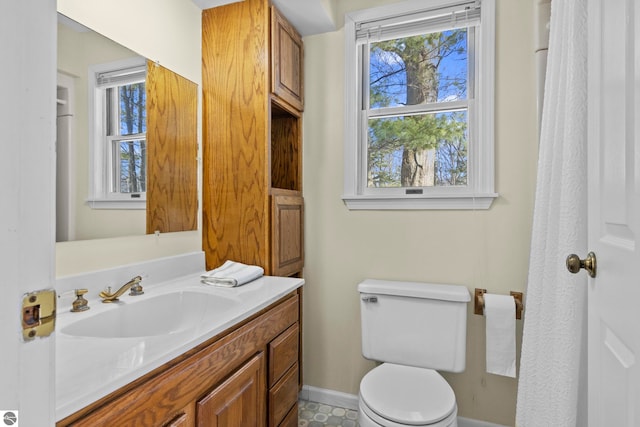 half bath featuring plenty of natural light, baseboards, toilet, and vanity