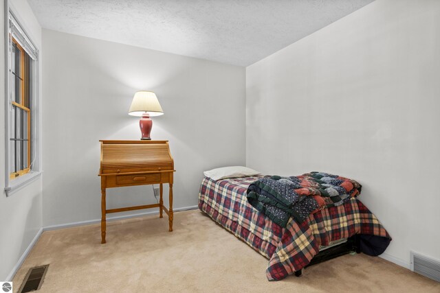 bedroom with carpet floors, a textured ceiling, and visible vents
