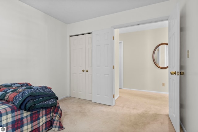 bedroom with a closet, baseboards, and light colored carpet