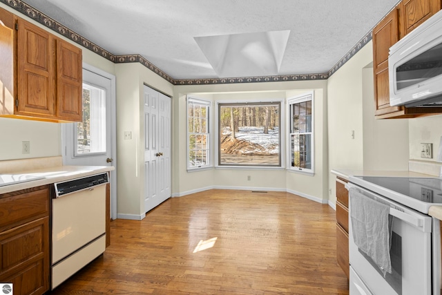 kitchen featuring white appliances, light countertops, light wood-style flooring, and a healthy amount of sunlight