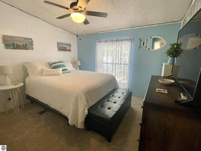 bedroom featuring lofted ceiling, carpet floors, a textured ceiling, and a ceiling fan