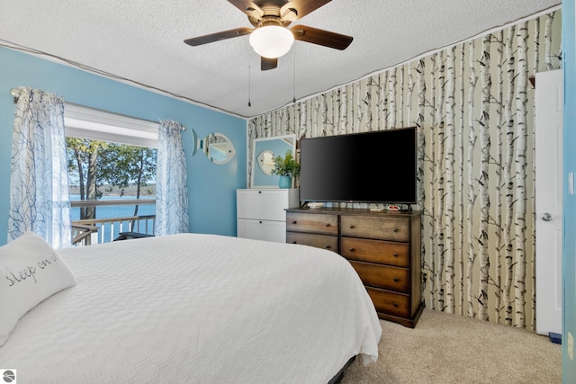bedroom with carpet flooring, a textured ceiling, a ceiling fan, and an accent wall