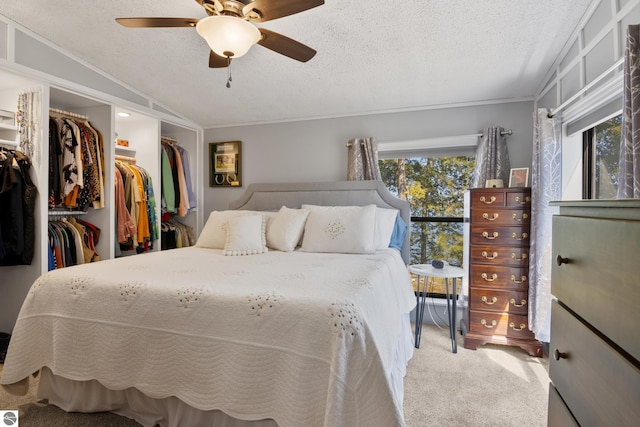 bedroom featuring carpet, a textured ceiling, crown molding, a ceiling fan, and a spacious closet