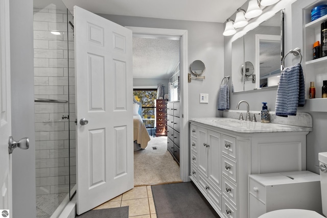 ensuite bathroom featuring a tile shower, tile patterned flooring, and vanity