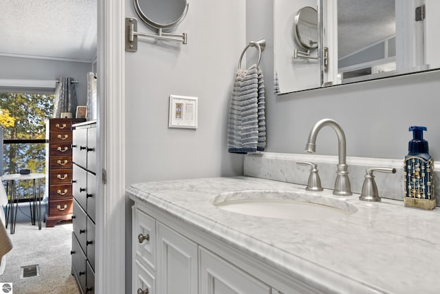 bathroom featuring a textured ceiling, vanity, and ornamental molding