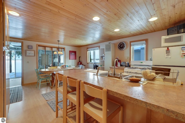 kitchen featuring wood ceiling, a kitchen bar, white appliances, and light wood-style flooring
