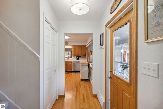 corridor featuring light wood-style flooring and a baseboard heating unit