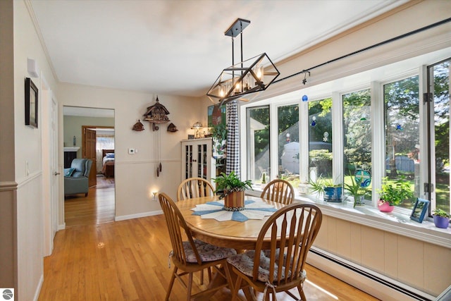 dining area with a baseboard radiator, plenty of natural light, and light wood-type flooring