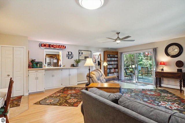 living area featuring a ceiling fan, light wood-style floors, a baseboard heating unit, and baseboard heating