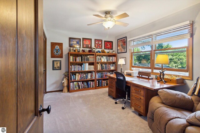 office space with baseboards, a ceiling fan, and light carpet