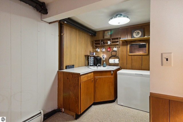 laundry area with a baseboard radiator, wood walls, an AC wall unit, and a sink
