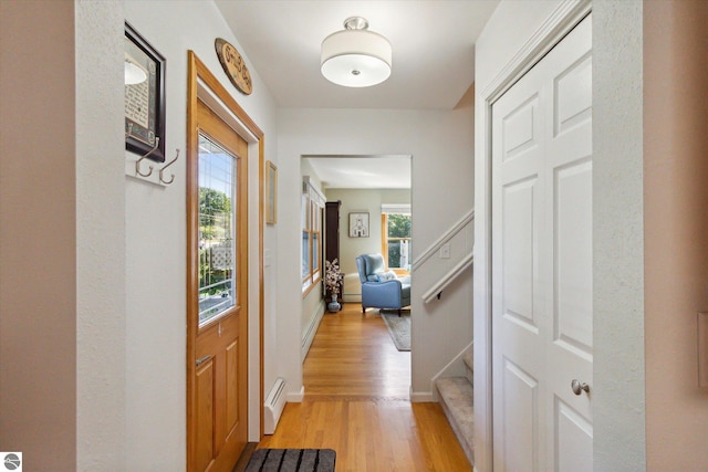 hall featuring baseboards, stairs, light wood-style floors, and baseboard heating