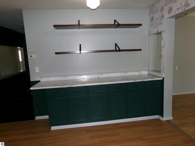 kitchen featuring open shelves, wallpapered walls, light wood-type flooring, green cabinets, and baseboards