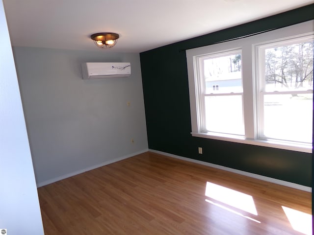 empty room with baseboards, wood finished floors, and an AC wall unit