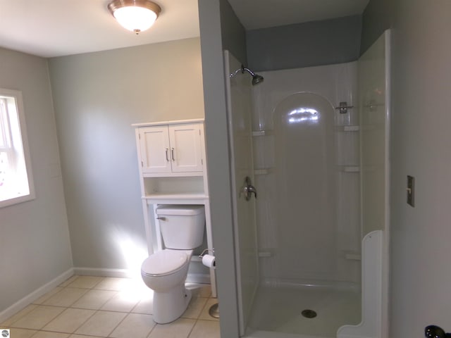 bathroom featuring tile patterned flooring, a shower stall, toilet, and baseboards