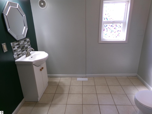 half bathroom with baseboards, toilet, vanity, and tile patterned floors