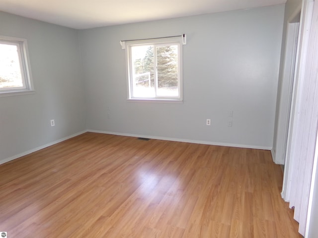 spare room featuring light wood-style floors, visible vents, and baseboards