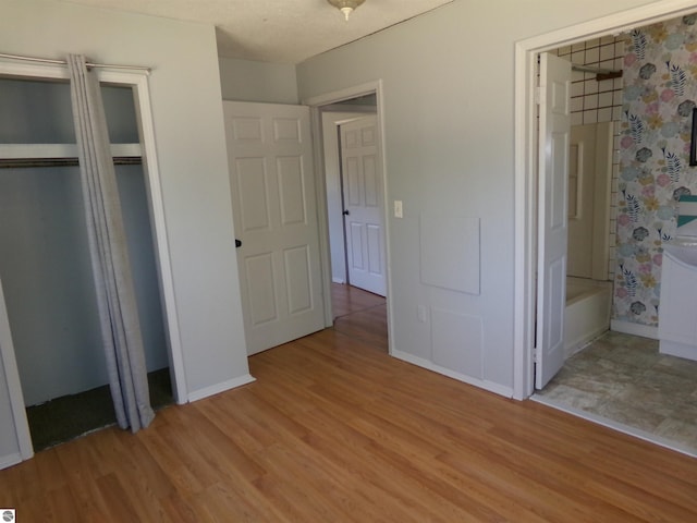 unfurnished bedroom with light wood finished floors, baseboards, and a closet