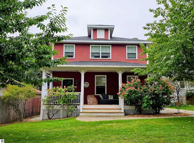 american foursquare style home with covered porch and a shingled roof