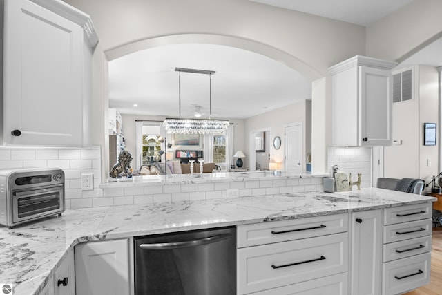kitchen featuring stainless steel dishwasher, arched walkways, white cabinets, and decorative backsplash