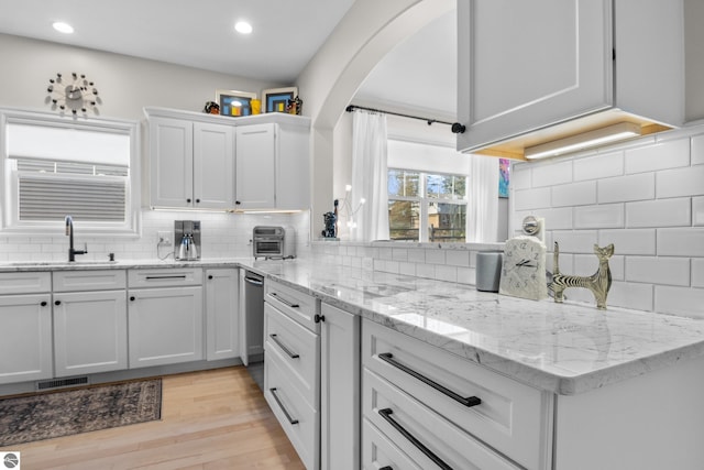 kitchen featuring a sink, decorative backsplash, white cabinetry, light wood-style floors, and recessed lighting
