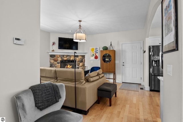 living area featuring a stone fireplace and light wood finished floors