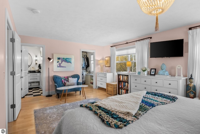 bedroom with light wood-style flooring, connected bathroom, a closet, and baseboards