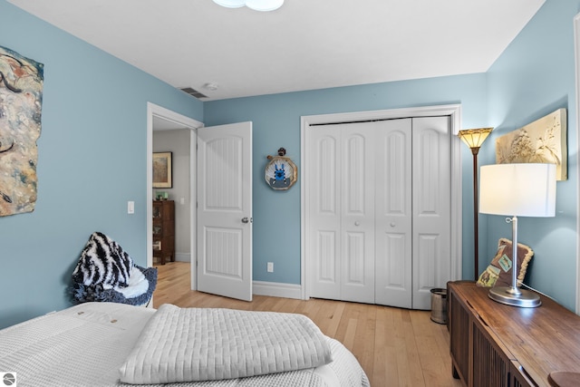 bedroom featuring light wood finished floors, a closet, and baseboards