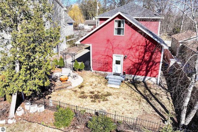 rear view of house featuring fence and roof with shingles