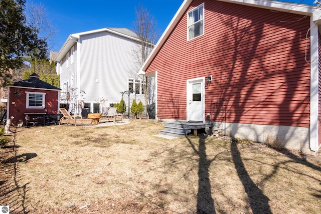 back of property with an outdoor structure, a shed, and a patio area