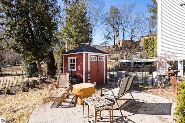 view of patio with an outbuilding, fence, and a shed