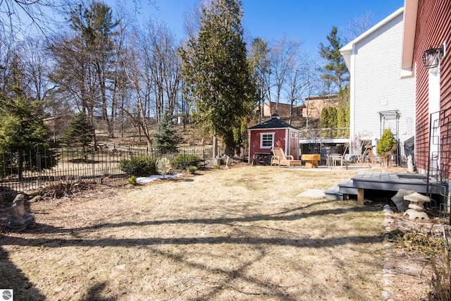 view of yard with a wooden deck, an outbuilding, and fence