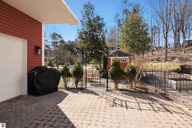 view of patio featuring a grill, fence, and a garage