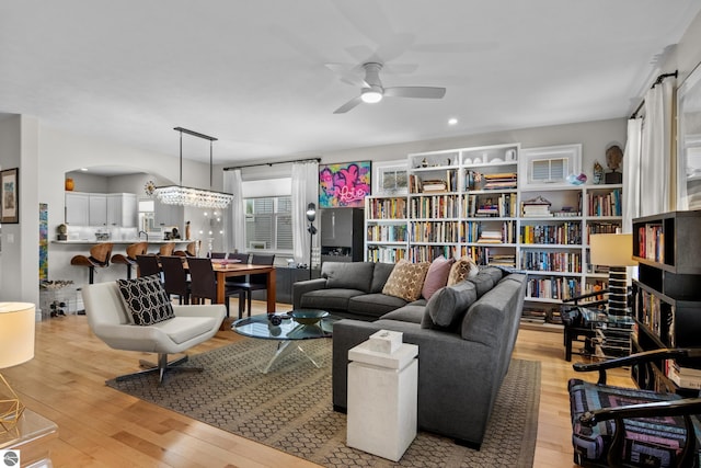 living room featuring a ceiling fan, light wood-type flooring, and arched walkways