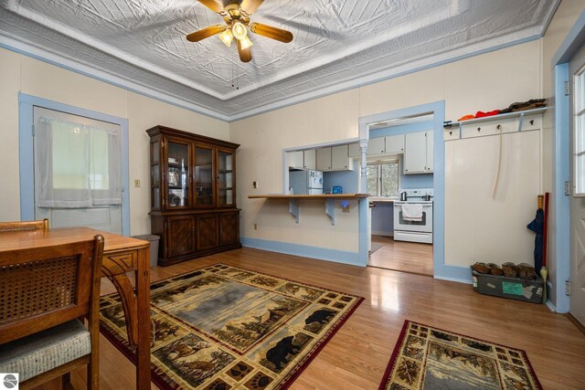 dining room with an ornate ceiling, crown molding, a raised ceiling, wood finished floors, and ceiling fan