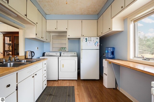 kitchen featuring a sink, freestanding refrigerator, dark wood-style floors, baseboards, and independent washer and dryer