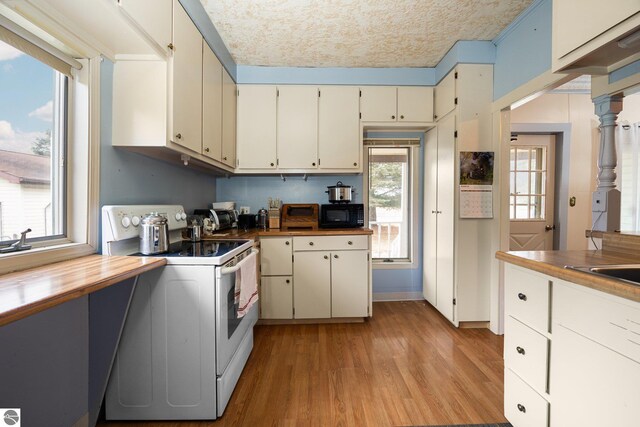 kitchen with black microwave, butcher block countertops, a textured ceiling, electric stove, and light wood-style floors