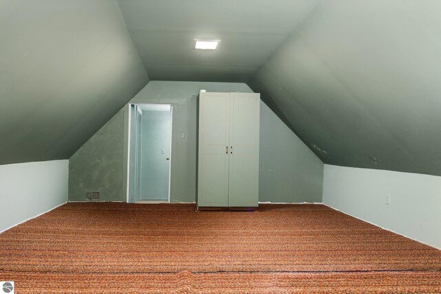 additional living space with visible vents, vaulted ceiling, and carpet