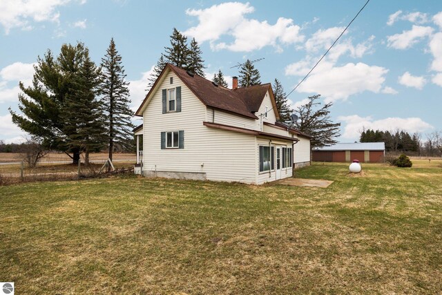 view of side of property featuring fence, a yard, and a chimney