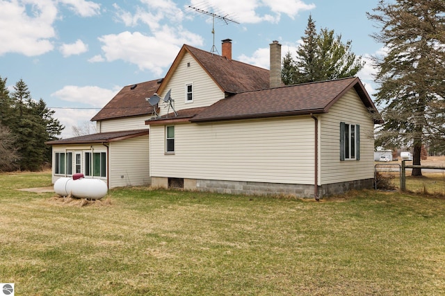 back of house featuring a yard, a shingled roof, and fence