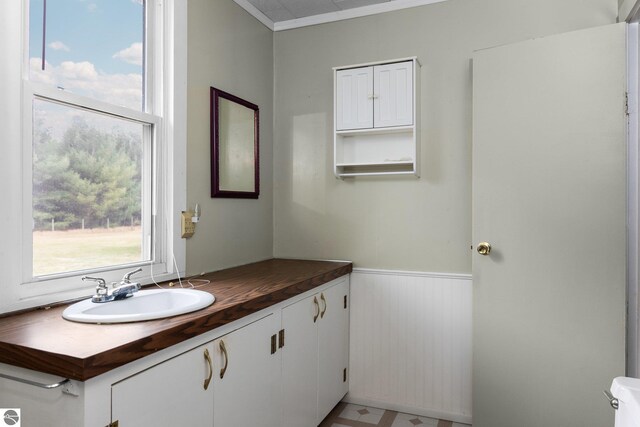 bathroom with a wainscoted wall, tile patterned floors, and vanity