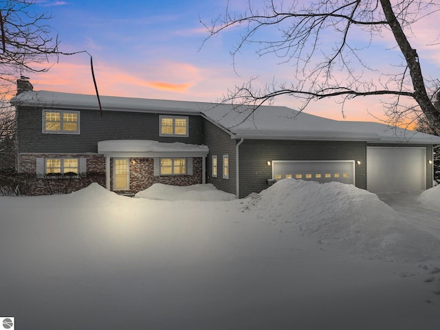 800 Evart St, Cadillac, MI 49601 - view of front of house featuring an attached garage, brick siding, driveway, and a chimney