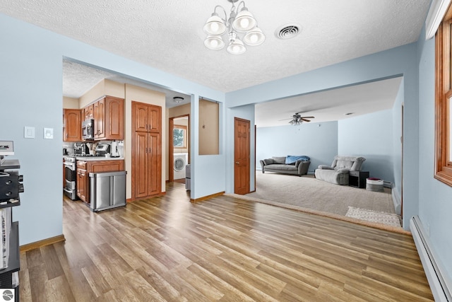 800 Evart St, Cadillac, MI 49601 - interior space with baseboard heating, light wood-style floors, a textured ceiling, washer / clothes dryer, and visible vents