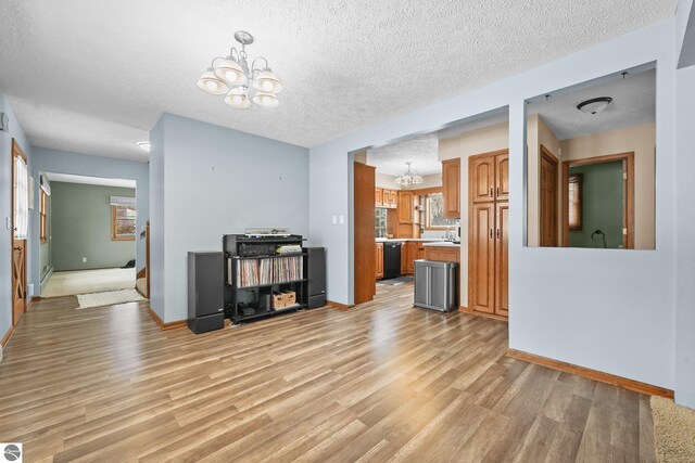 800 Evart St, Cadillac, MI 49601 - unfurnished living room with an inviting chandelier, a textured ceiling, light wood-style floors, and baseboards