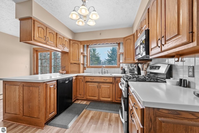 800 Evart St, Cadillac, MI 49601 - kitchen with light wood-style flooring, a textured ceiling, appliances with stainless steel finishes, and a notable chandelier