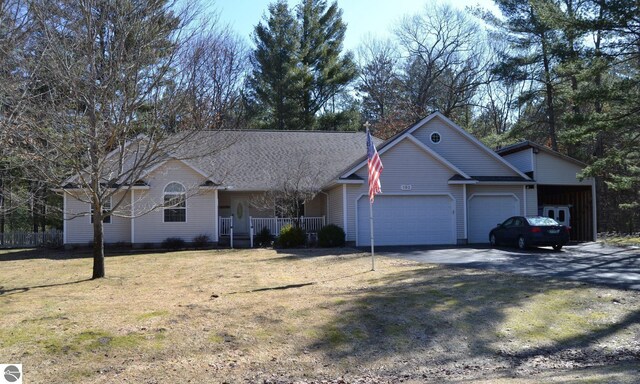 102 James Sq, Roscommon, MI 48653 - view of front facade featuring a garage, dirt driveway, a front yard, and a porch
